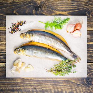 two kippers on a board with shallots, herbs and seasoning